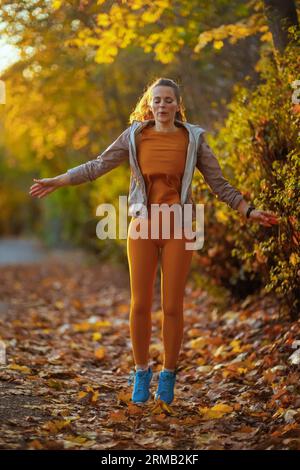 Hallo Herbst. Portrait der stilvollen Frau in Fitnesskleidung im Park, der sich nach dem Workout entspannt. Stockfoto