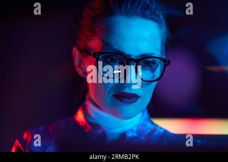 Neon-Metaverse-futuristisches Konzept. Porträt einer trendigen Frau mit Laptop. Stockfoto