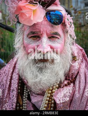 London, Großbritannien, 27. August 2023. Ein Reveller in rosa Outfit und Kopfschmuck sitzt in der Nähe der Spitze des Notting Hill, um sich von den Festlichkeiten zu erholen. Es wird erwartet, dass bis zu zwei Millionen Menschen den Karneval an diesem Feiertagswochenende feiern und an Soundsystemen, Ständen und Veranstaltungsorten entlang der Karnevalsroute teilnehmen oder zusehen. Bunte Pulver und Farben, in Anerkennung der karibischen Tradition und Beginn der Karnevalsfeste in Notting Hill. Quelle: Imageplotter/Alamy Live News Stockfoto