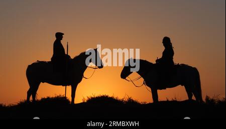 Mann und Frau auf einer Camargue oder Camarguais Horse in den Dünen bei Sunrise, Manadier in der Camargue im Südosten Frankreichs, Les Saintes Maries de l Stockfoto