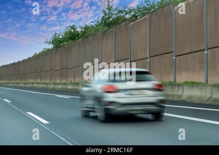 Verschwommene Autos im schallabsorbierenden Tunnel auf der Asphaltstraße. Metallstruktur mit Kunststoffteilen. Stockfoto