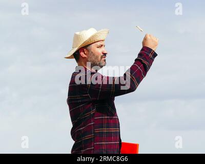 Porträt eines Bauern-Mannes mit Hut bei der Untersuchung von Weizen. Konzept des ökologischen Landbaus Stockfoto