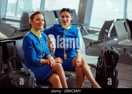 Fröhliche Frauen Stewardessen warten auf den Flug am Flughafen Stockfoto