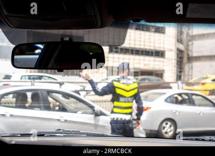 Verkehrspolizist in der Mitte der Straße, die den Verkehr in der belebten Straße in Amman Jordanien regelt. Verschwommenes Bild eines Verkehrspolizisten Stockfoto