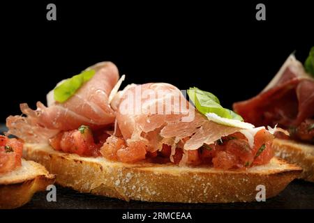 Köstliches Bruschetta garniert mit geräuchertem Lachs, Schinken und Parmesan Stockfoto