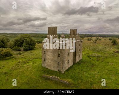 Luftaufnahme der Burg Glinsk mittelalterliches befestigtes Turmhaus in Irland mit symmetrischer Struktur fünf lange hohe Schornsteine auf jeder Seite, County Calway Stockfoto