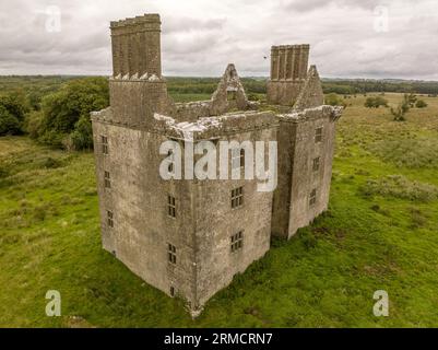 Luftaufnahme der Burg Glinsk mittelalterliches befestigtes Turmhaus in Irland mit symmetrischer Struktur fünf lange hohe Schornsteine auf jeder Seite, County Calway Stockfoto