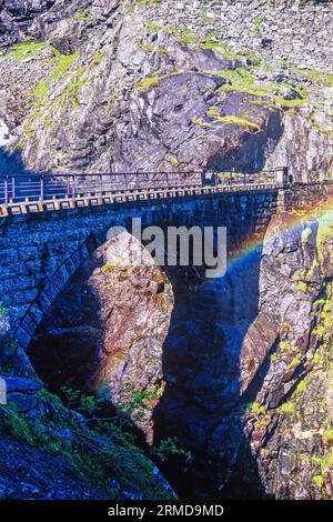 Alte Bogenbrücke mit Regenbogen auf einem Berg Stockfoto