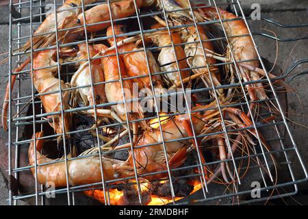 Viele riesige Süßwassergarnelen werden im Grill über dem Holzkohlefeuer gegrillt. Seine Farbe ist orange, sieht appetitlich aus. Stockfoto