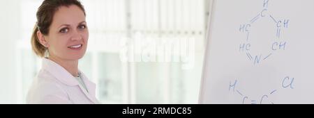 Eine glückliche Frau schreibt eine chemische Formel auf ein Whiteboard Stockfoto