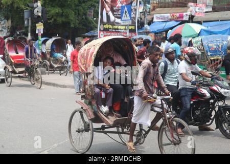 Dhaka, Bangladesch. August 27, 2023. Eine allgemeine Ansicht zeigt, dass Rikscha-Abzieher ihre Kunden in den Verkehr auf der New Market Road in DH transportieren Stockfoto