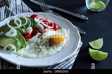 Spiegelei und Avocado, Tomaten, Gemüse auf weißem Teller. Konzept des gesunden Frühstücks. Draufsicht, flach liegend. Leerzeichen kopieren. Stockfoto