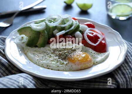 Spiegelei und Avocado, Tomaten, Gemüse auf weißem Teller. Konzept des gesunden Frühstücks. Draufsicht, flach liegend. Leerzeichen kopieren. Stockfoto