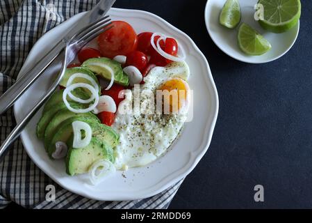 Spiegelei und Avocado, Tomaten, Gemüse auf weißem Teller. Konzept des gesunden Frühstücks. Draufsicht, flach liegend. Leerzeichen kopieren. Stockfoto