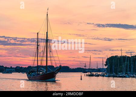 Segelschiffe Auf Dem Warnow Bei Sonnenuntergang Während Der Hanse Sail In Rostock. Stockfoto
