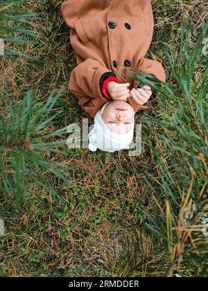 Ein kleines Kind liegt auf dem Boden und lächelt. Draufsicht. Das Konzept der Herbstblätter für Kinder. Ein Lächeln im Gesicht eines Kindes. Ein kleines Kind in einem Stockfoto