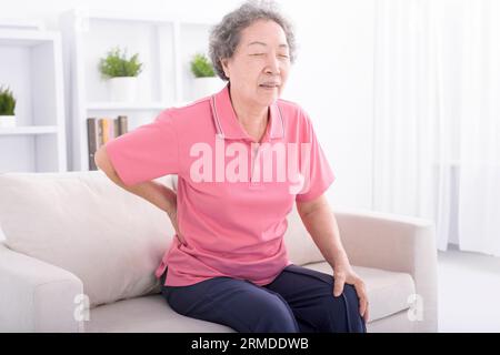Ältere Frau mit Rückenbeschwerden zu Hause Stockfoto