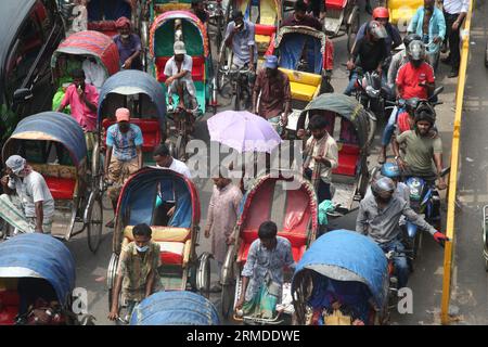 Dhaka, Bangladesch. August 27, 2023. Eine allgemeine Ansicht zeigt, dass Rikscha-Abzieher ihre Kunden in den Verkehr auf der New Market Road in DH transportieren Stockfoto