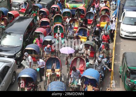 Dhaka, Bangladesch. August 27, 2023. Eine allgemeine Ansicht zeigt, dass Rikscha-Abzieher ihre Kunden in den Verkehr auf der New Market Road in DH transportieren Stockfoto