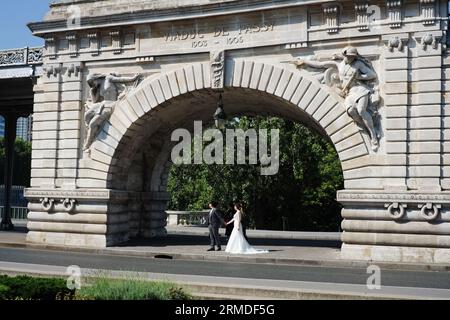 Ein Hochzeitsshooting mit einem Bräutigam und einer Braut in weißem Kleid unter dem monumentalen Steinbogen, Viaduct de Passy Pont de Bir-Hakeim, Paris; Frankreich; Stockfoto
