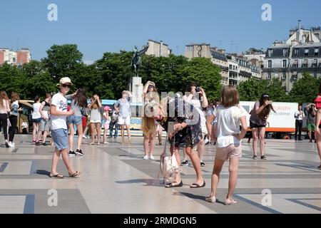 Am Place du Trocadéro beugt sich eine Mutter doppelt und fotografiert an einem sonnigen Sommertag ihre kleine Tochter mit „Pariser schönster Aussicht auf den Eiffelturm“ Stockfoto