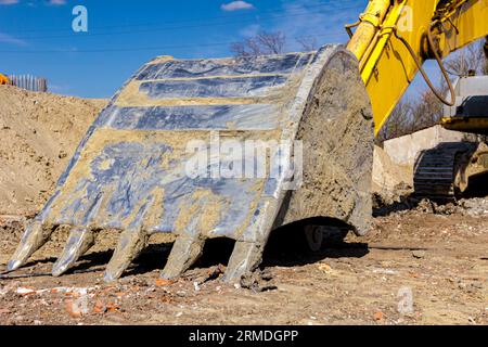 Frontwerkzeug des Baggers, Löffel, Schild, auf der Baustelle geparkt. Stockfoto