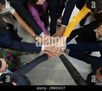 Team-, Teamwork- und Einheitskonzept. Ein vielfältiges Team, das die Hände zusammenbringt. Gruppe verschiedener Geschäftsleute. Zusammenarbeit als Team. Partnerschaft und Stockfoto