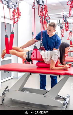 Eine junge Frau macht Übungen mit speziellen Seilen im Rehabilitationszentrum. Stockfoto