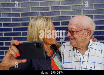 Zwei Generationen, die ein Selfie machen oder Videoanrufe mit einem Smartphone im Freien führen Stockfoto