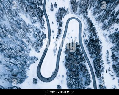 Kurvige Straße durch verschneite Wälder von oben, Maloja Pass, Schweiz Stockfoto