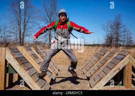 Ein Mann mit Rucksack springt über Rampen auf einem Hindernisparcours draußen Stockfoto