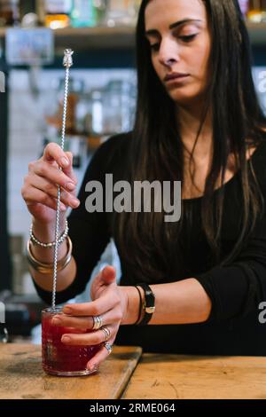 Die junge Barfrau bereitet einen alkoholischen Cocktail in der Bar zu. Stockfoto