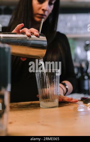 Die junge Barfrau bereitet einen alkoholischen Cocktail in der Bar zu. Stockfoto