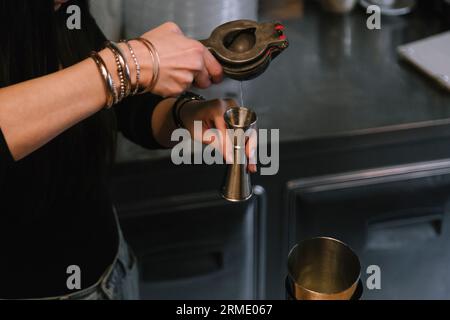 Die junge Barfrau bereitet einen alkoholischen Cocktail in der Bar zu. Detail Stockfoto