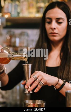Die junge Barfrau bereitet einen alkoholischen Cocktail in der Bar zu Stockfoto