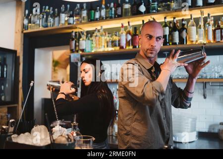 Zwei junge Barmänner bereiten einen alkoholischen Cocktail in der Bar zu Stockfoto