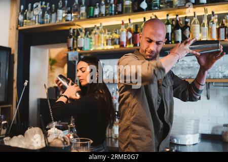 Zwei junge Barmänner bereiten einen alkoholischen Cocktail in der Bar zu Stockfoto