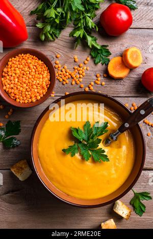 Rote Linsen- und Gemüsesuppe auf hölzernem Hintergrund. Traditionelle Küche aus dem Nahen Osten, türkisch, ramadan. Veganes Komfortessen - Gemüsesuppe. Stockfoto