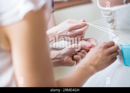 Brautjungfern helfen der Braut, ihr Hochzeitskleid anzuziehen Stockfoto