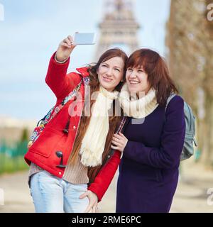 Zwei fröhlich schöne Mädchen in Paris machen Selfie in der Nähe des Eiffelturms Stockfoto