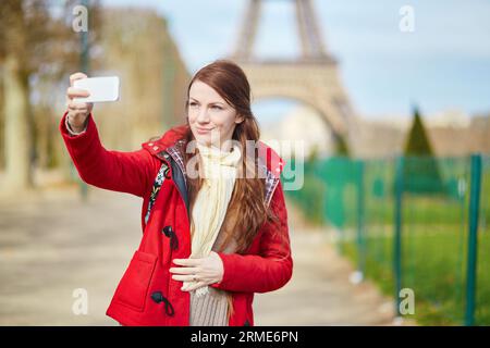 Schöne junge Touristen in Paris, die sich mit ihrem Handy in der Nähe des Eiffelturms selbst fotografieren (Selfie) Stockfoto