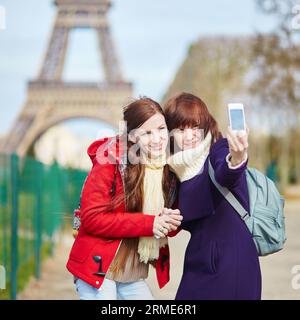 Zwei fröhlich schöne Mädchen in Paris machen Selfie in der Nähe des Eiffelturms Stockfoto