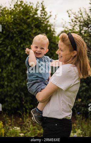 Mutter und Kleinkind teilen sich fröhliche Spielzeit im Garten Stockfoto