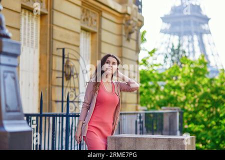 Junge schöne und elegante Pariser Frau in rosa Kleid in der Nähe des Eiffelturms in Paris Stockfoto