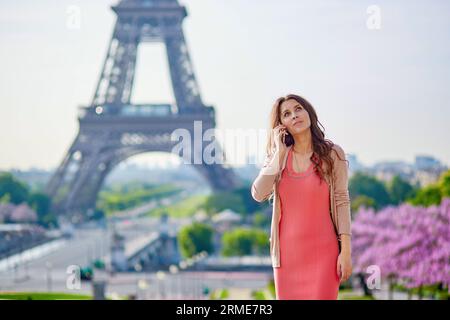 Junge schöne und elegante Pariser Frau in rosa Kleid in der Nähe des Eiffelturms in Paris Stockfoto