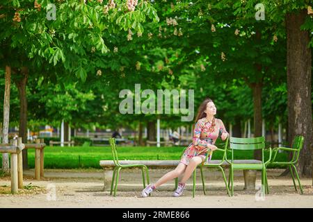 Schöne junge Frau im Tuileriegarten, die unter Kastanienbäumen in voller Blüte spaziert Stockfoto