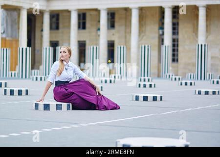 Fröhliche junge Frau im langen Rock Palais Royal in Paris Stockfoto