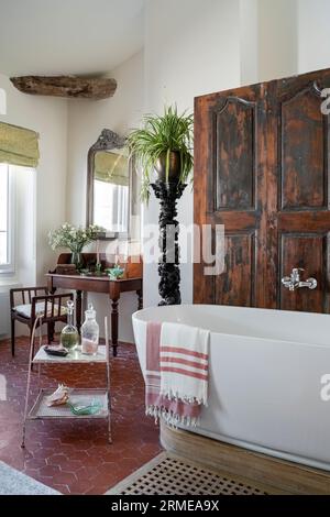 Die restaurierten Holztüren verbergen eine Dusche mit kunstvoller Fackel und einen Vintage-Waschtisch im Cotignac-Badezimmer, Var, Frankreich. Stockfoto