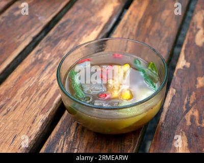 Eine Schüssel Sayur ASEM, Tamarindensuppe, eine beliebte indonesische Suppe, auf Holztisch. Stockfoto