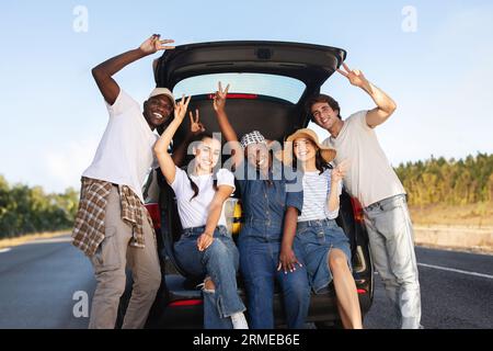 Positive multikulturelle Junggesellen, die gemeinsam mit dem Auto unterwegs sind Stockfoto